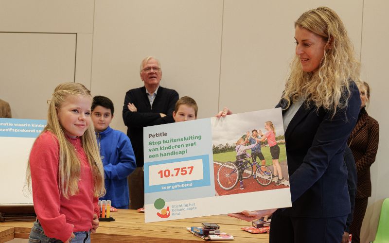 Kinderambassadeur Feline geeft een bord aan staatssecretaris Vicky Maeijer 