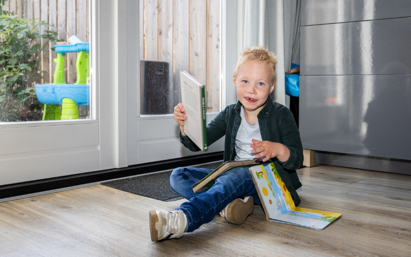 Jayce op de grond met een boekje in zijn handen