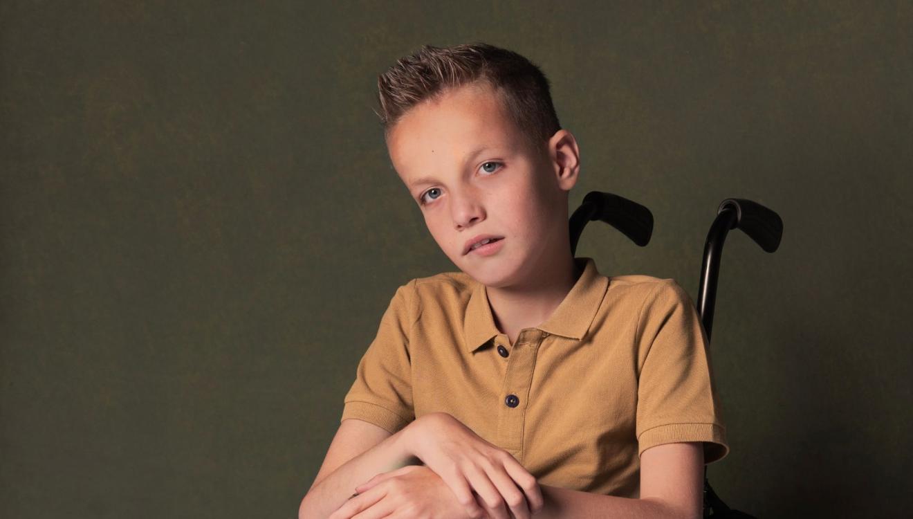 Sem zit in zijn rolstoel en kijkt in de camera