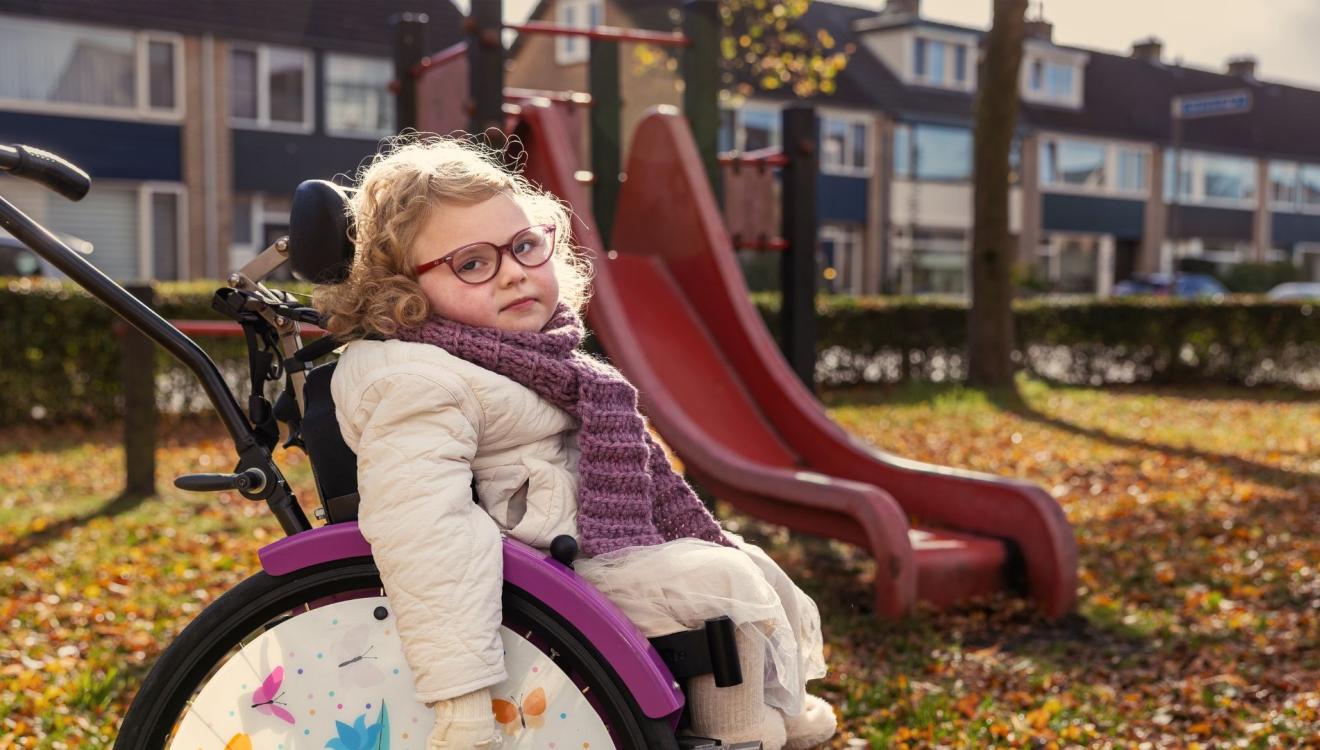 Minthe zit voor de speeltuin in haar rolstoel