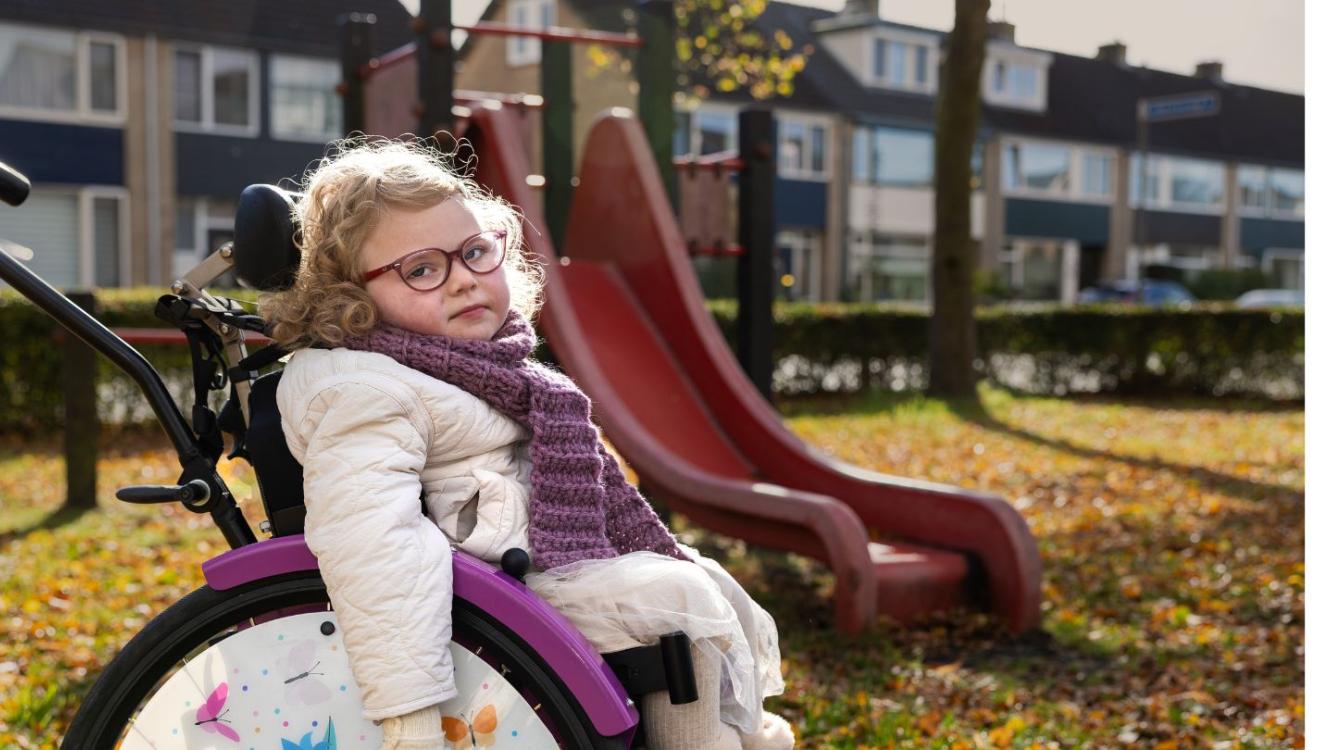 Minthe zit voor de speeltuin in haar rolstoel