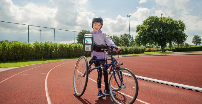 Keet met een collectebus in haar hand op haar runningframe 