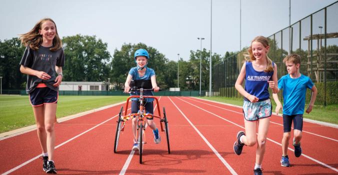 Kinderen met en zonder handicap samen aan het rennen over de atletiekbaan