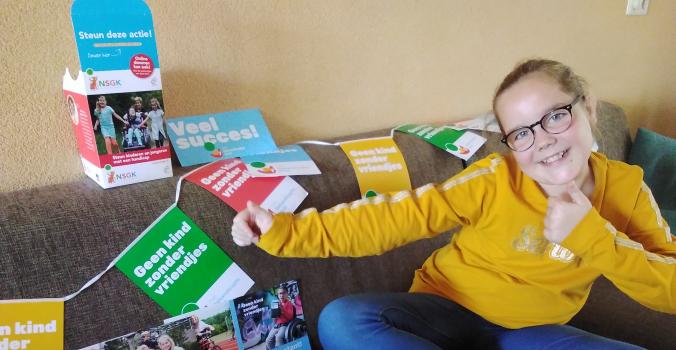 Elise Verheijen met folders en vlaggetjes van Het Gehandicapte Kind op de bank