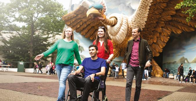 Bezoeker in een rolstoel met gezelschap lopend in de Efteling