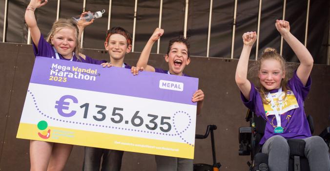 Kinderambassadeurs Feline, Art, Thomas en Vesper met de cheque van de Mega Wandel Marathon