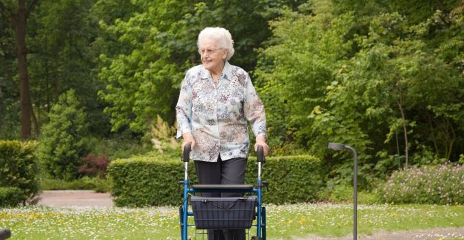 Tante Gerda met haar rollator door een park aan het lopen