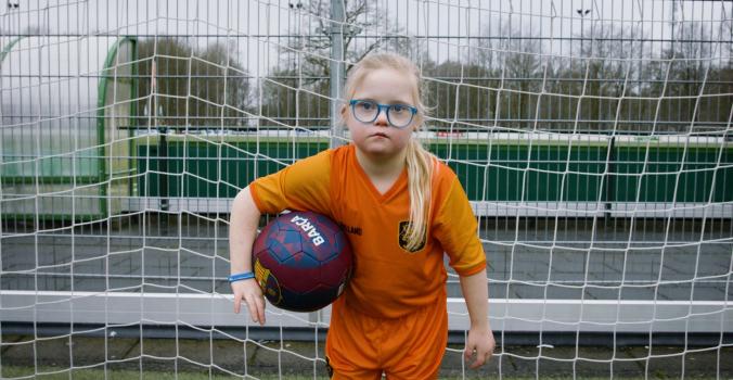 Lotte staat in het doel met een voetbal onder haar arm