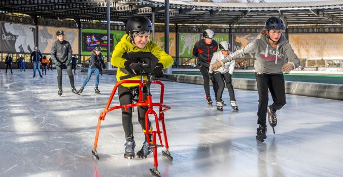 Hidde op zijn schaatsframe aan het schaatsen met leeftijdsgenootjes