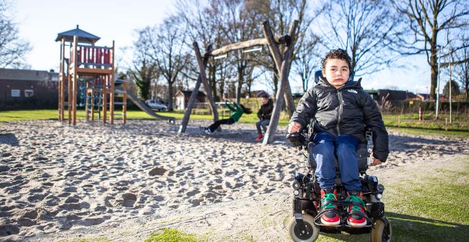 Ira in zijn rolstoel voor de speeltuin