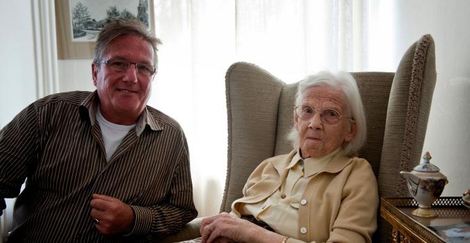 Mevrouw Neijboer in haar stoel met haar neef naast zich