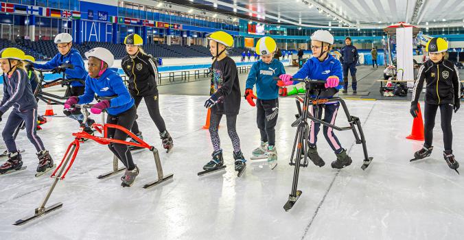 Kinderen met een beperking op een schaatsframe aan het schaatsen en naast hun schaatsen kinderen zonder beperking | Frame Schaatsen