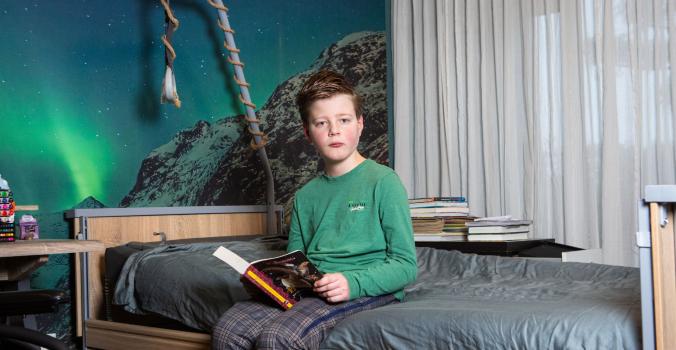 Vince zit op zijn bed met een boek