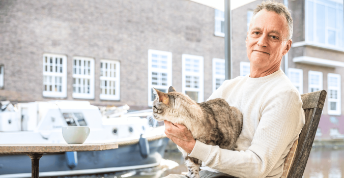 Foto van Ian Helgering met zijn kat Hector op schoot bij een raam.