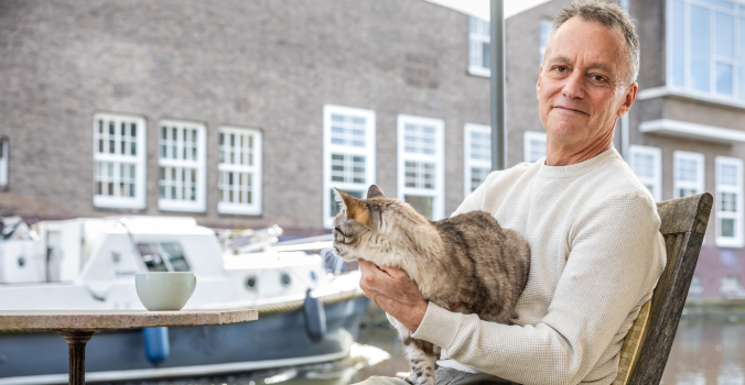 Foto van Ian Helgering met zijn kat Hector op schoot bij een raam.
