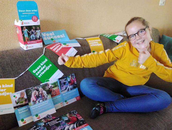 Elise Verheijen met folders en vlaggetjes van Het Gehandicapte Kind op de bank
