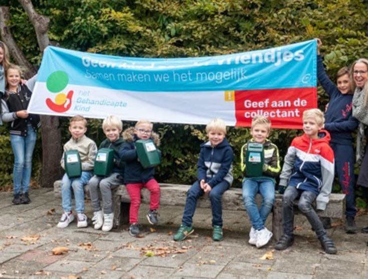 Collectevrijwillger Sabine met kinderen voor een spandoek