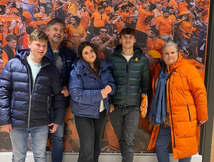 Niels en zijn familie voor een fotowand van Oranje