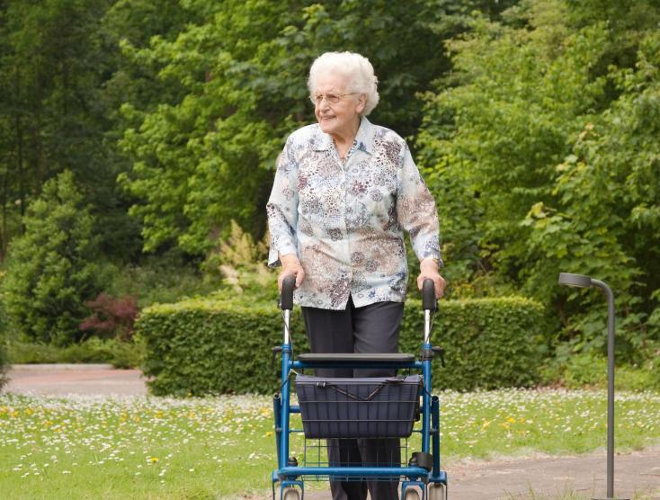 Tante Gerda met haar rollator door een park aan het lopen