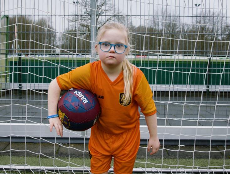 Lotte staat in het doel met een voetbal onder haar arm