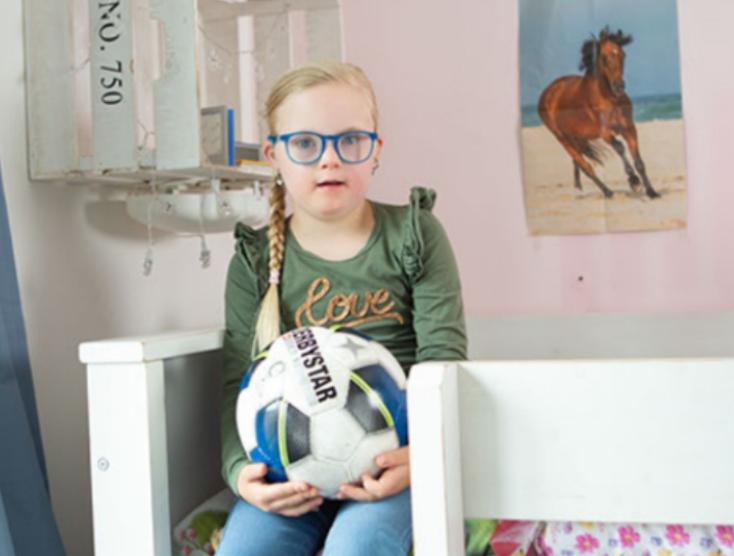 Lotte zit alleen op haar bed met een voetbal op haar schoot