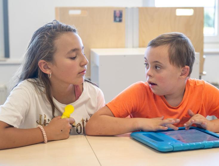 Kind zonder beperking helpt kind met beperking in de klas
