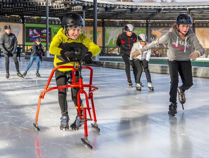 Hidde op zijn schaatsframe aan het schaatsen met leeftijdsgenootjes