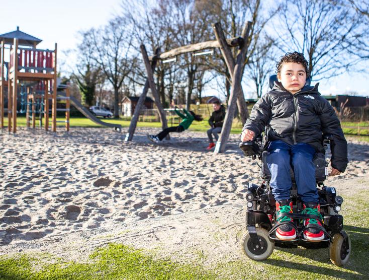 Ira in zijn rolstoel voor de speeltuin