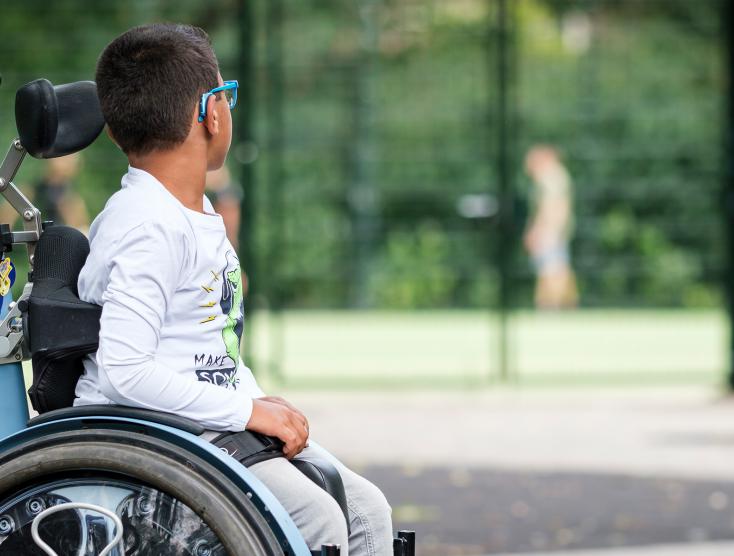 Jayden zit in een rolstoel en kijkt naar spelende kinderen