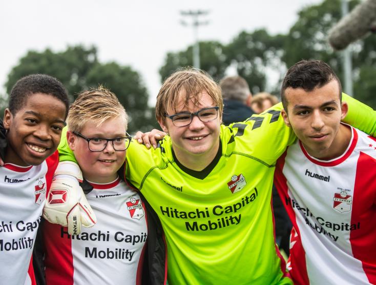 Vier jongens in voetbaltenue met de armen over elkaars schouders | Samen Sporten
