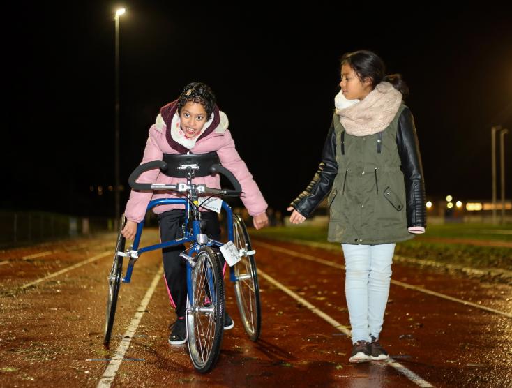 Twee kinderen waarvan één met handicap op de atletiekbaan met een Running Frame