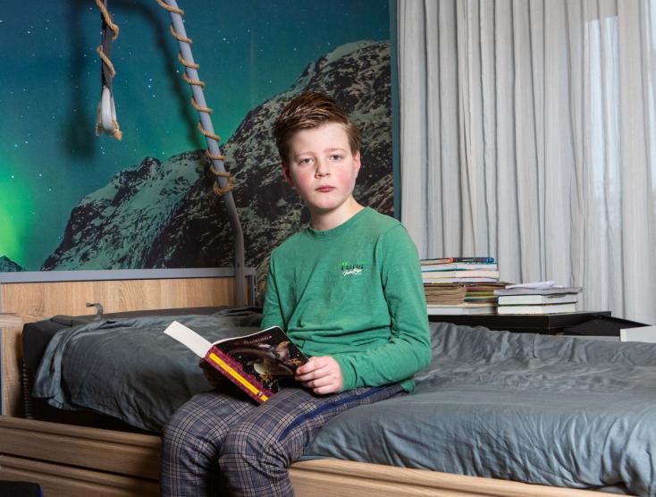 Vince zit op zijn bed met een boek