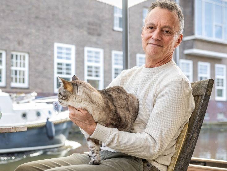 Foto van Ian Helgering met zijn kat Hector op schoot bij een raam.