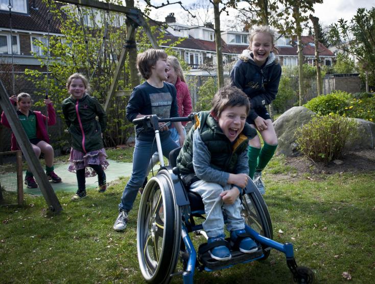 Kinderen met en zonder handicap samen aan het spelen in een speeltuin